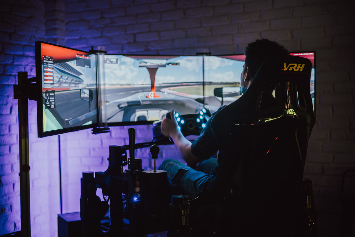 Driver racing on a VRH triple-screen simulator with VRH bucket seat and ambient lighting